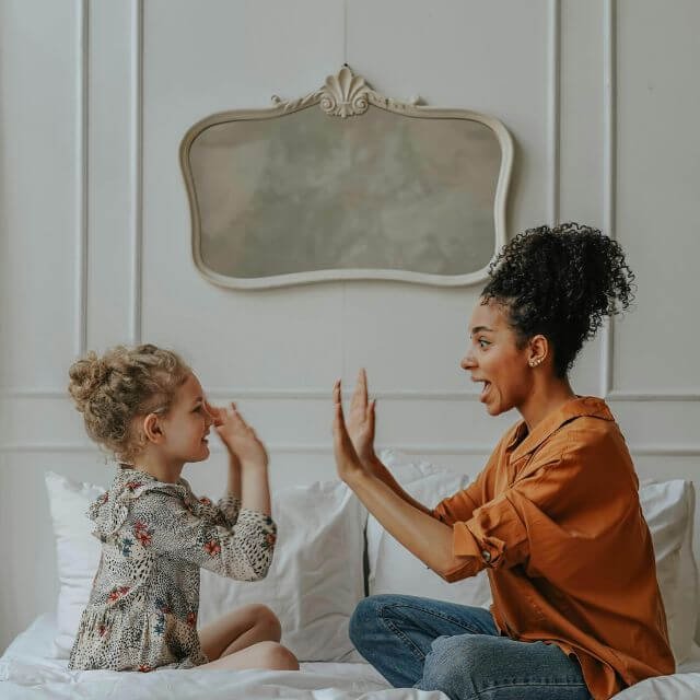 mère et fille faisant un jeu improvisé dans une chambre d'hôtel un jour de pluie