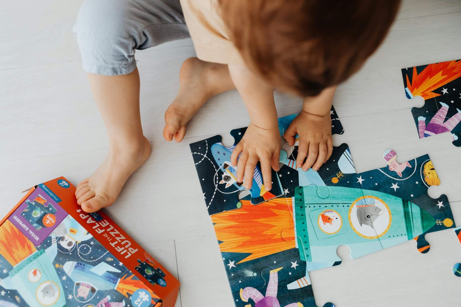 jeune enfant réalisant un puzzel assis par terre dans une chambre d'hôtel