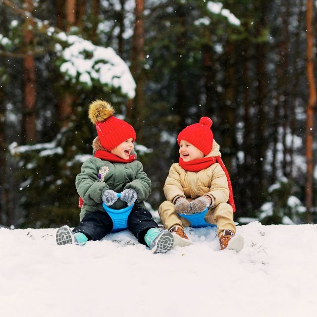 deux jeunes enfant riant en faisant de la luge sur la neige