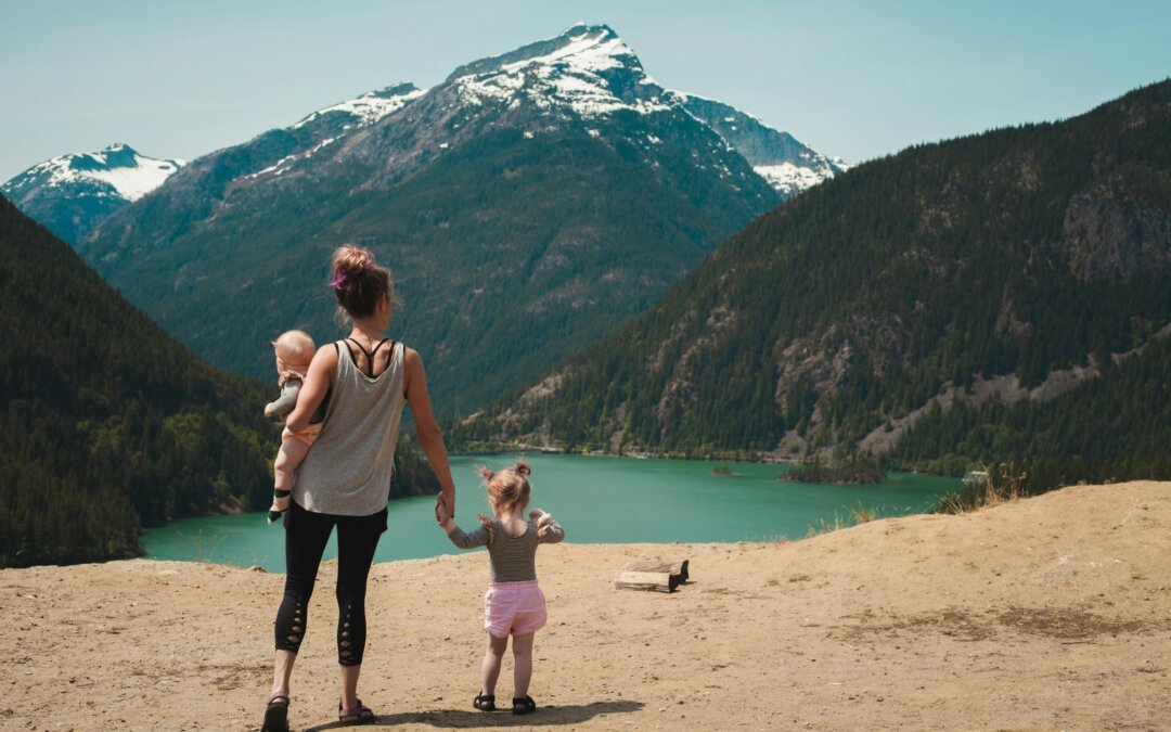 mère avec ses deux jeunes enfants regardant un lac dans la montagne