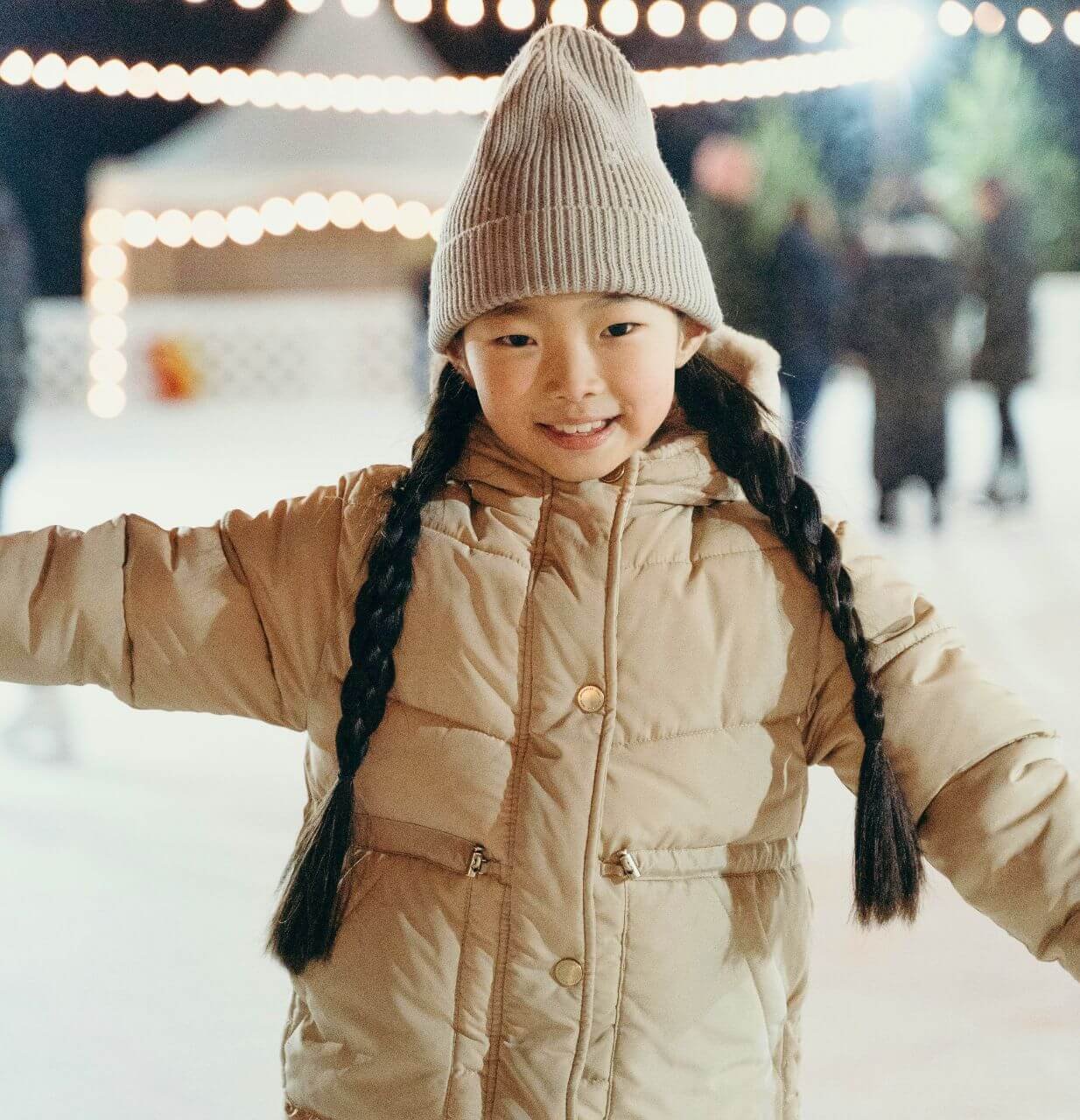 Jeune fille souriant en faisant du patin à glace bien habillée pour affronter le froid