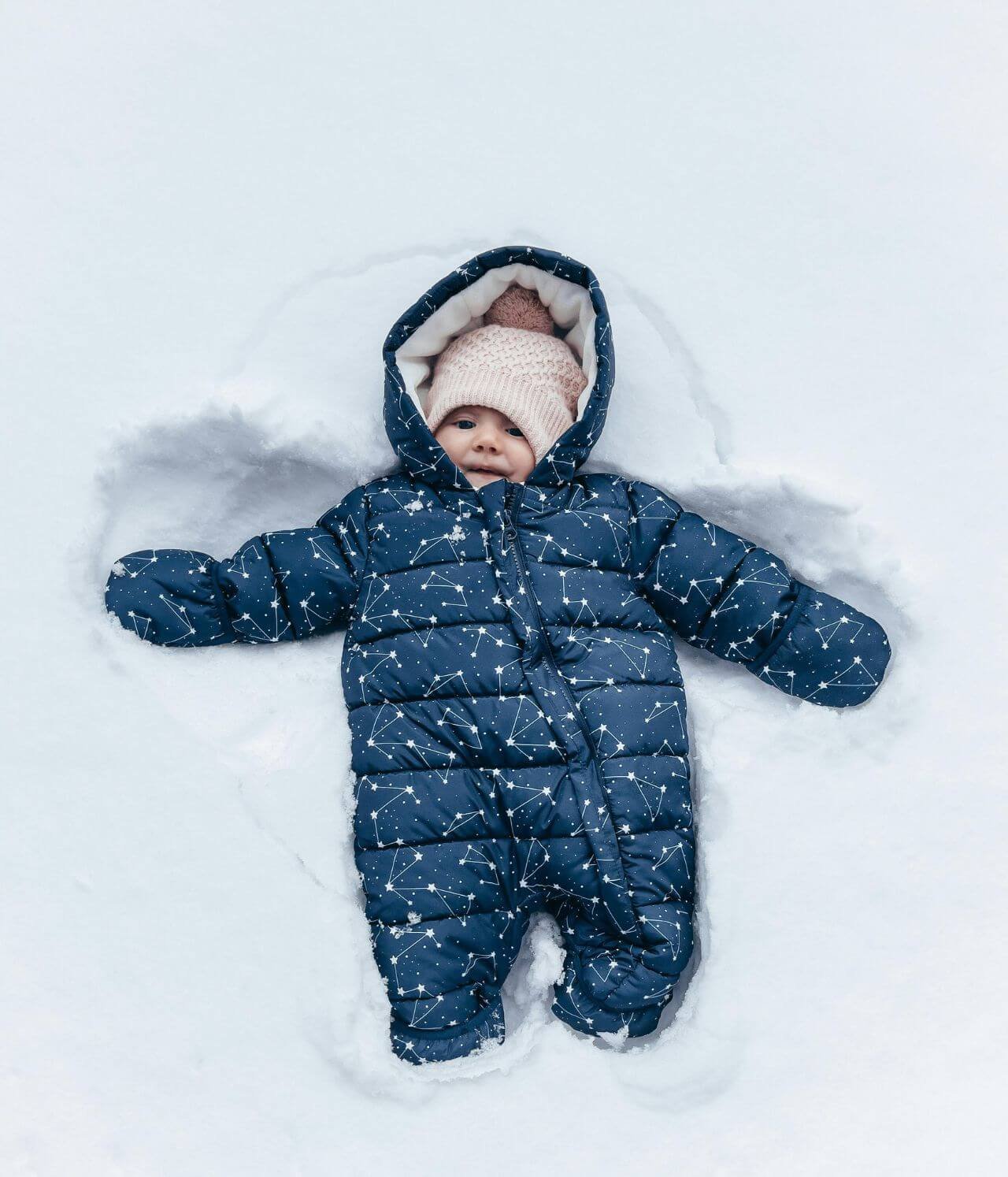 bébé habillé avec des vêtements grand froid qui joue dans la neige